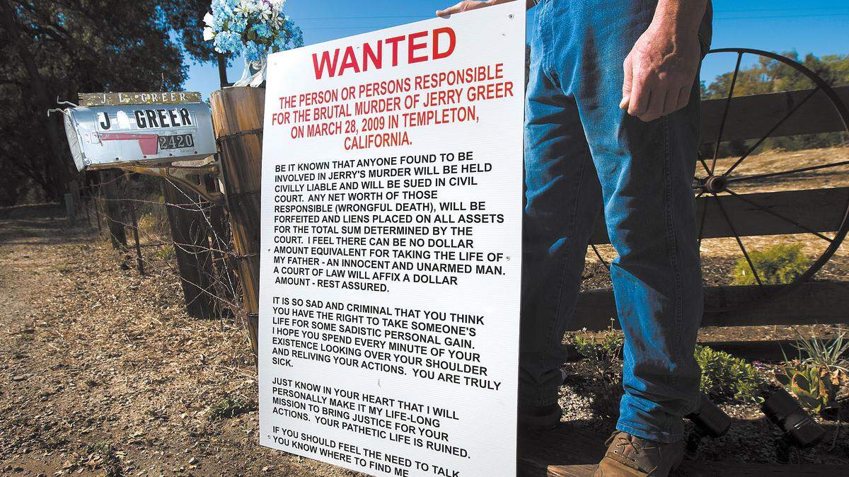 Brian Greer holds a wanted sign he made for the person who killed his father, Jerry Greer, in 2009. The elder Greer was shot to death while sleeping in his Templeton home and the case is still unsolved. Brian Greer was named a person of interest in the case in August.