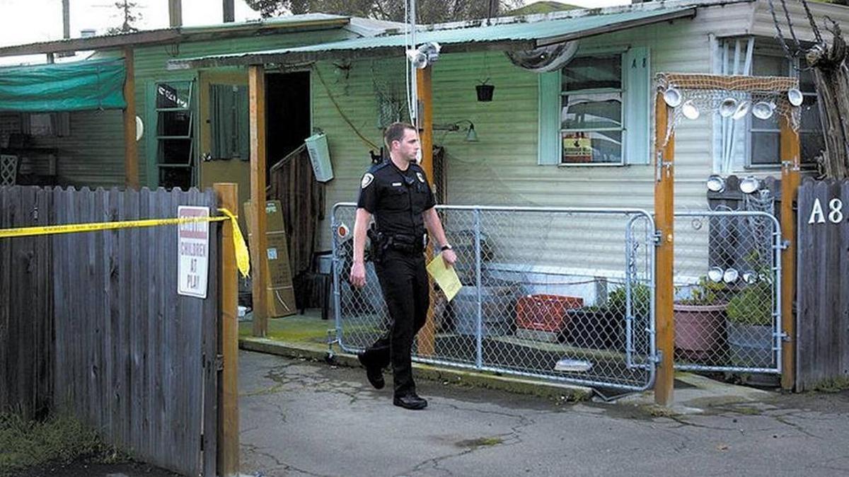 In this March 2005 photo, a San Luis Obispo police officer walks past the home of Gerald O’Malley, who was found dead inside by police.