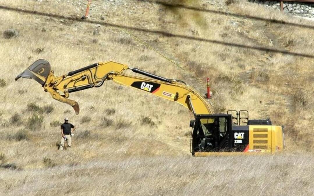 An investigator looks on Sept. 6 as a backhoe begins excavating work on a hillside near the Cal Poly “P,” which can be seen in the upper right corner. The Sheriff’s Office and the FBI were looking for evidence in Kristin Smart’s disappearance.