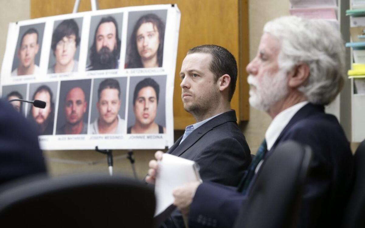 Chase Hanson, center, is accused of being the leader of a drug ring that sold cocaine and other substances. His attorney Jeffry Radding is seated at right. In the background are faces and names of those implicated in this investigation.