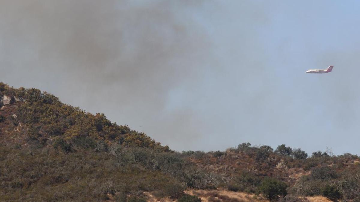 Firefighters worked in the steep hills near Huasna east of Arroyo Grande on Wednesday afternoon. An air tanker approaches for a drop.