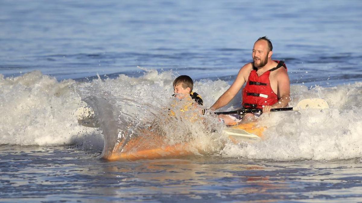 Nicholas Palma and his son Kainen, 8, of Nipomo have fun playing in small waves with their kayak at Avila Beach near Olde Port Beach.