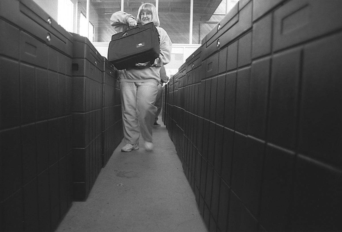 Pam Weaver picks up the electronic vote counting unit of the new ballot boxes she and others were testing Wednesday. The black boxes on either side are the new ballot boxes, they can sort and count ballots.
