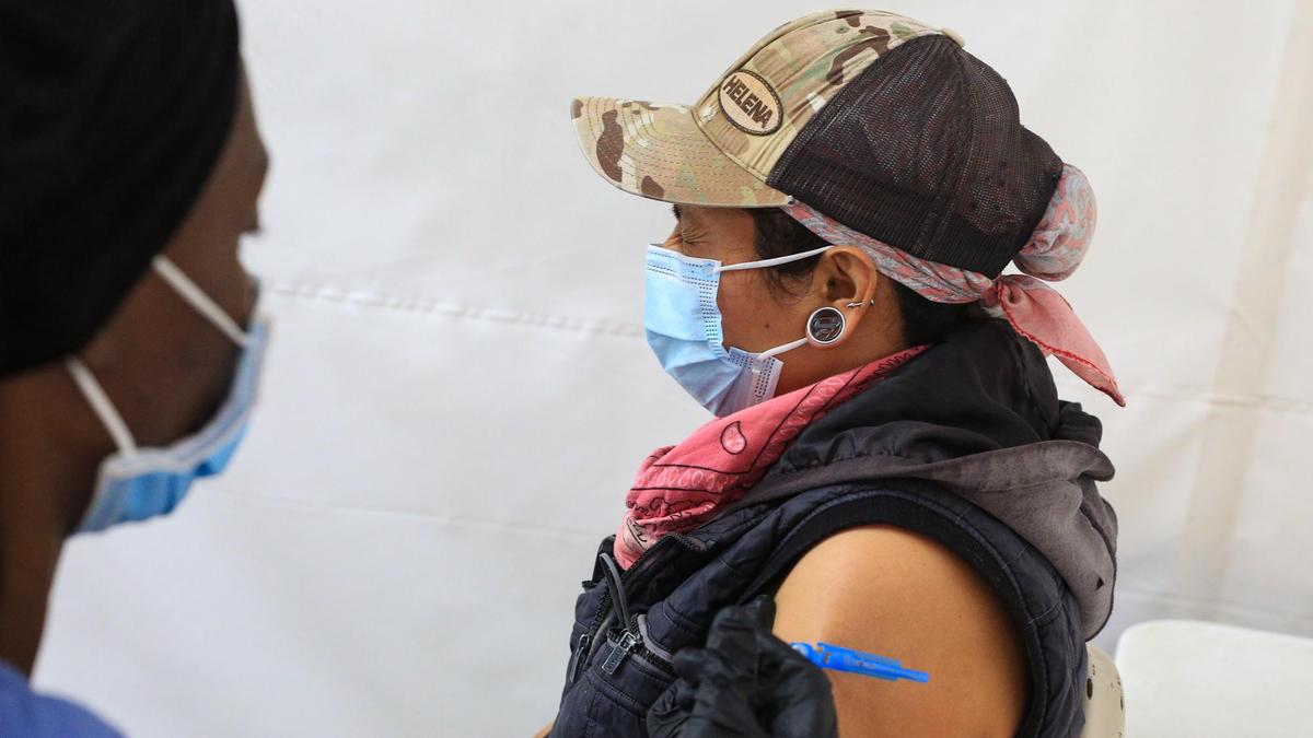 Sandra Barrientos closes her eyes while Kiera Torbert, a licensed vocational nurse, administers her COVID-19 shot at a San Luis Obispo County farmworker vaccine clinic held at the Paso Robles Event Center. 