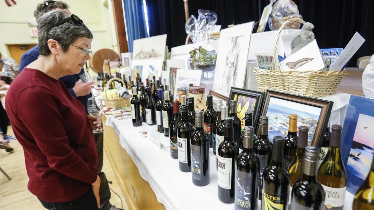 Kathy and Greg Poshepny of Cambria look at some of the wines being auctioned at the tasting event inside the Cambria Vets Hall, Sunday. This was their third time at the event, which she said is great for the businesses in town.