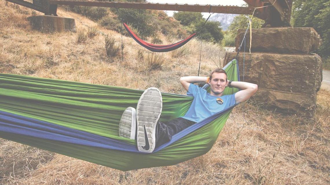 Carter Wilson, president and founder of the Cal Poly Hammock Club, rests in his hammock in June under the train trestle at Cal Poly.