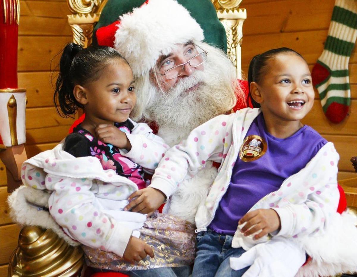 Sisters Cyenna, 4, and Natalya Fuston, 5, of Santa Maria sit on Santa’s lap at his house in Mission Plaza in 2015.