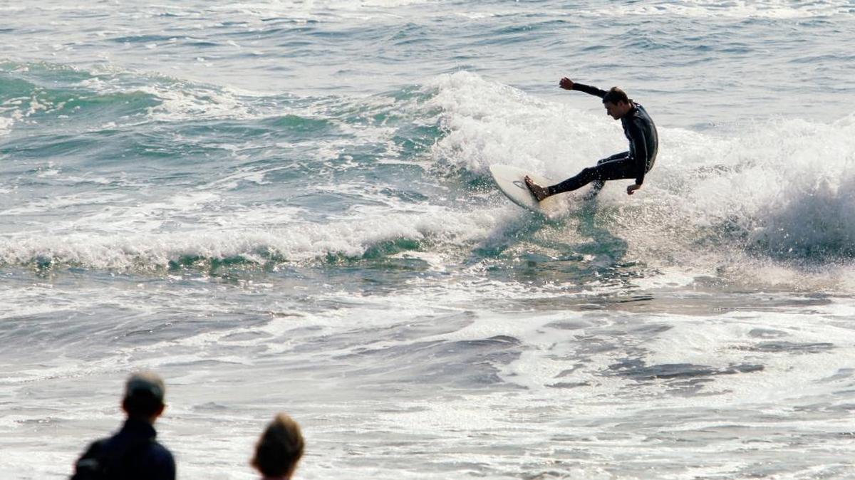 Beachgoers watch a surfer along Moonstone Drive in Cambria.