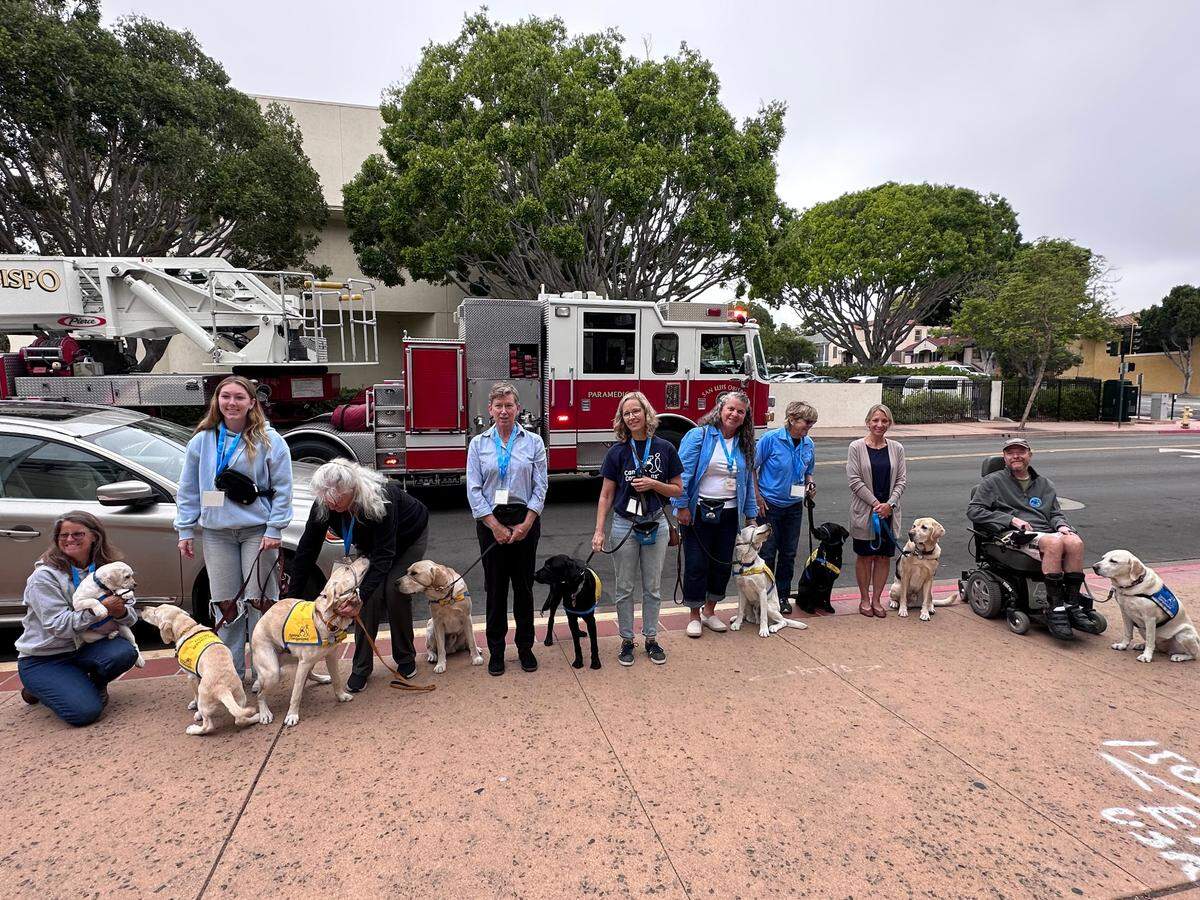 A fire alarm sounded at the San Luis Obispo County Board of Supervisors meeting on Tuesday, Sept. 12, 2023, prompting meeting attendees to evacuate. Members of the non profit organization Canine Companions wait for firefighters to clear the building so they can re-enter the meeting.