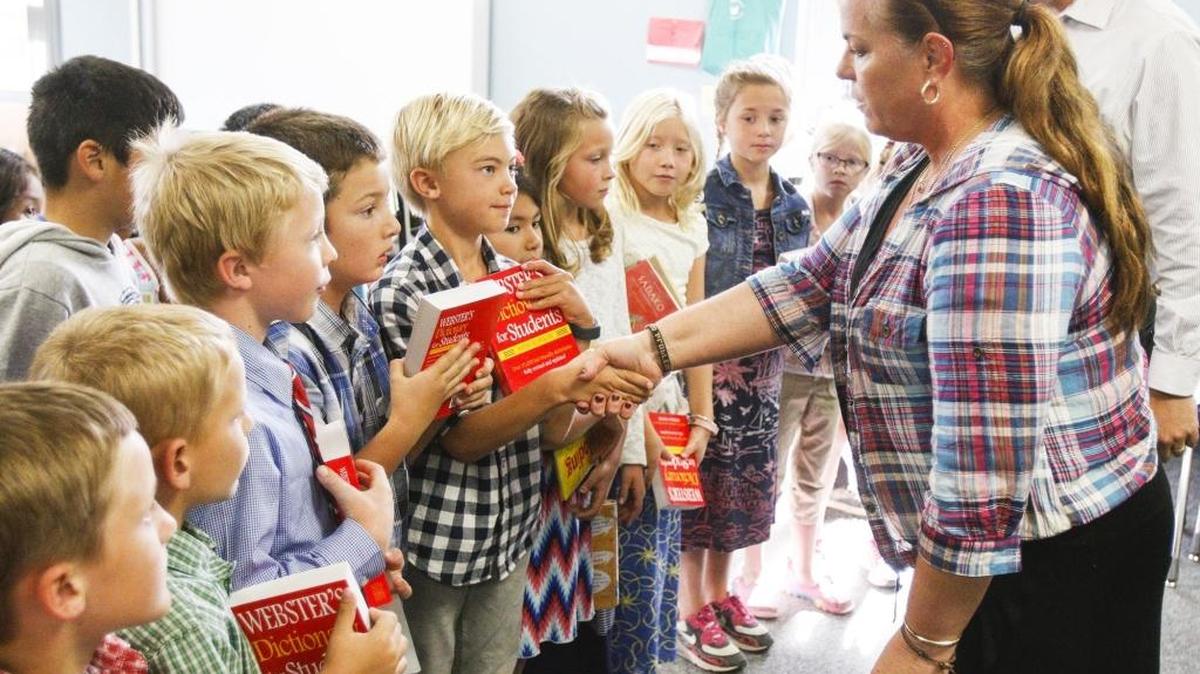 Kristen Handley hands a dictionary to third-grader Mason Taylor, 9, on Tuesday. The Templeton Chamber of Commerce and local service groups gave Vineyard Elementary School’s third-graders a dictionary and fourth-graders a thesaurus to take home to use with their homework.