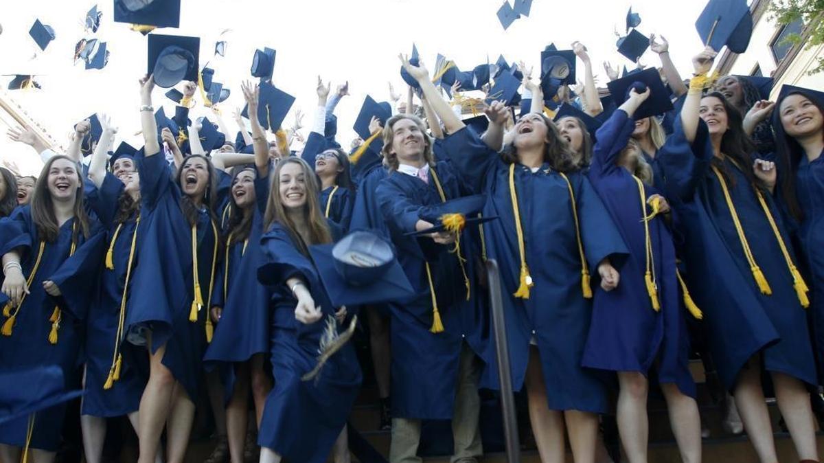 A bit out of order but full of spirit, students throw their caps while posing for photo Friday before the start of Mission Prep’s graduation.