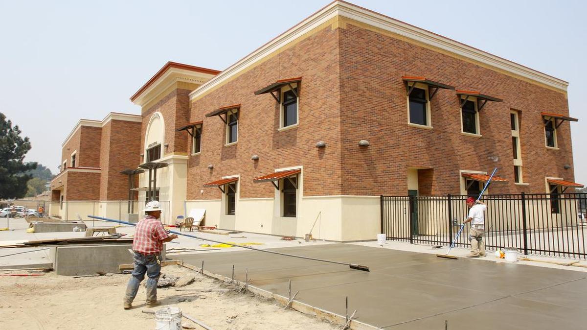 Marc Goyette, left, and Rodney Benson sweep a concrete sidewalk at Atascadero Middle School on Tuesday as the campus’ new building is being completed.