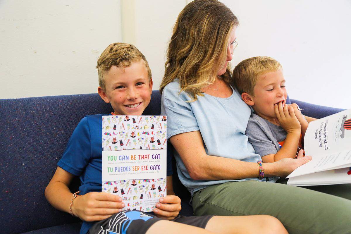 Lindsey Haring poses with her two sons, whose drawings inspired graphic illustration in the bilingual book, “You Can be That Cat.” Jack Haring is posing with the book to the left. Luke Haring is on the right.
