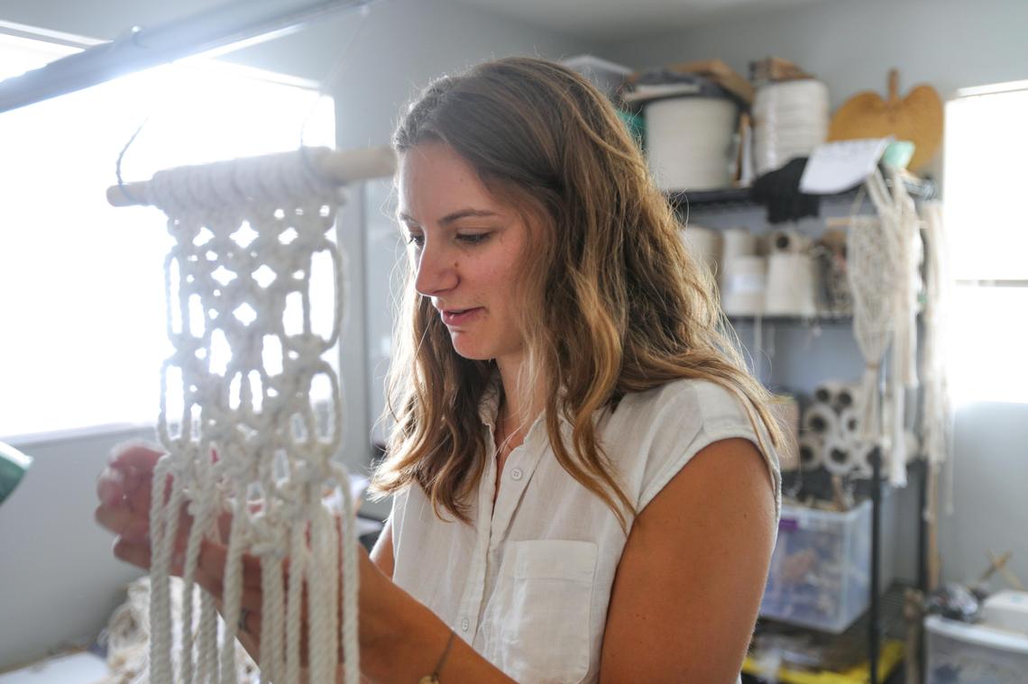 Lindsey Altman, who runs a side business selling macrame crafts, works on a piece in her home office. Since buying a house with her husband in Atascadero, she now has a whole room devoted to her business.