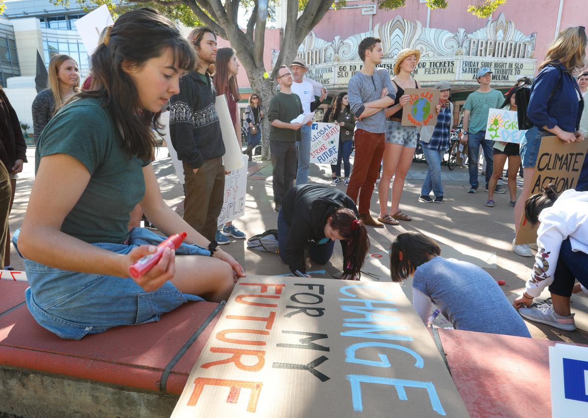 Tara Hale of Cal Poly finishes a sign in front of the County Government Center in San Luis Obispo on Friday, March 15, 2019. Students from Cal Poly, Cuesta College and local high schools walked out of class to rally for climate action.