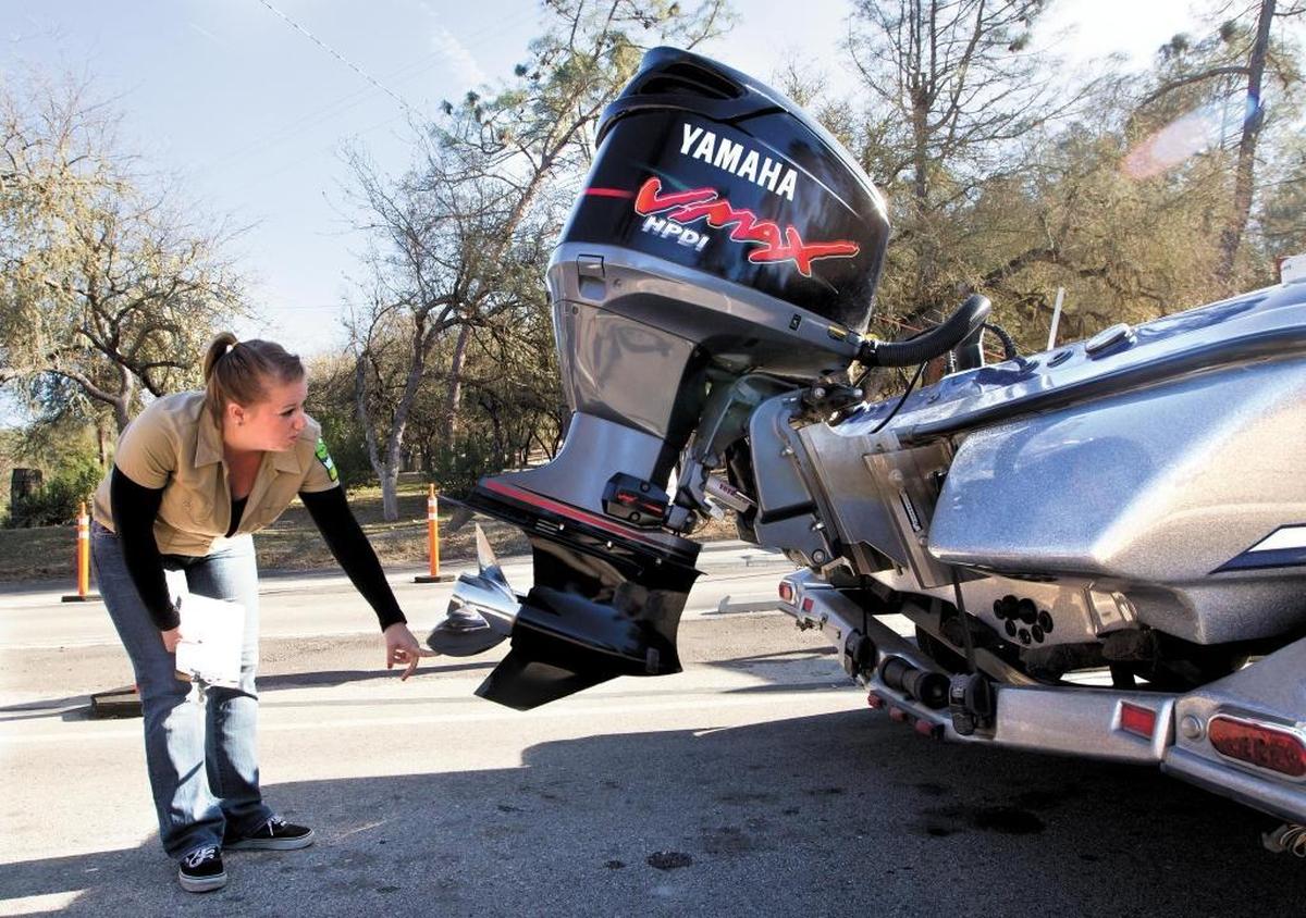 Kelley Petersen checks for quagga mussels on Dusty Kahler’s boat at the enterance to Lake Nacimiento in 2012.