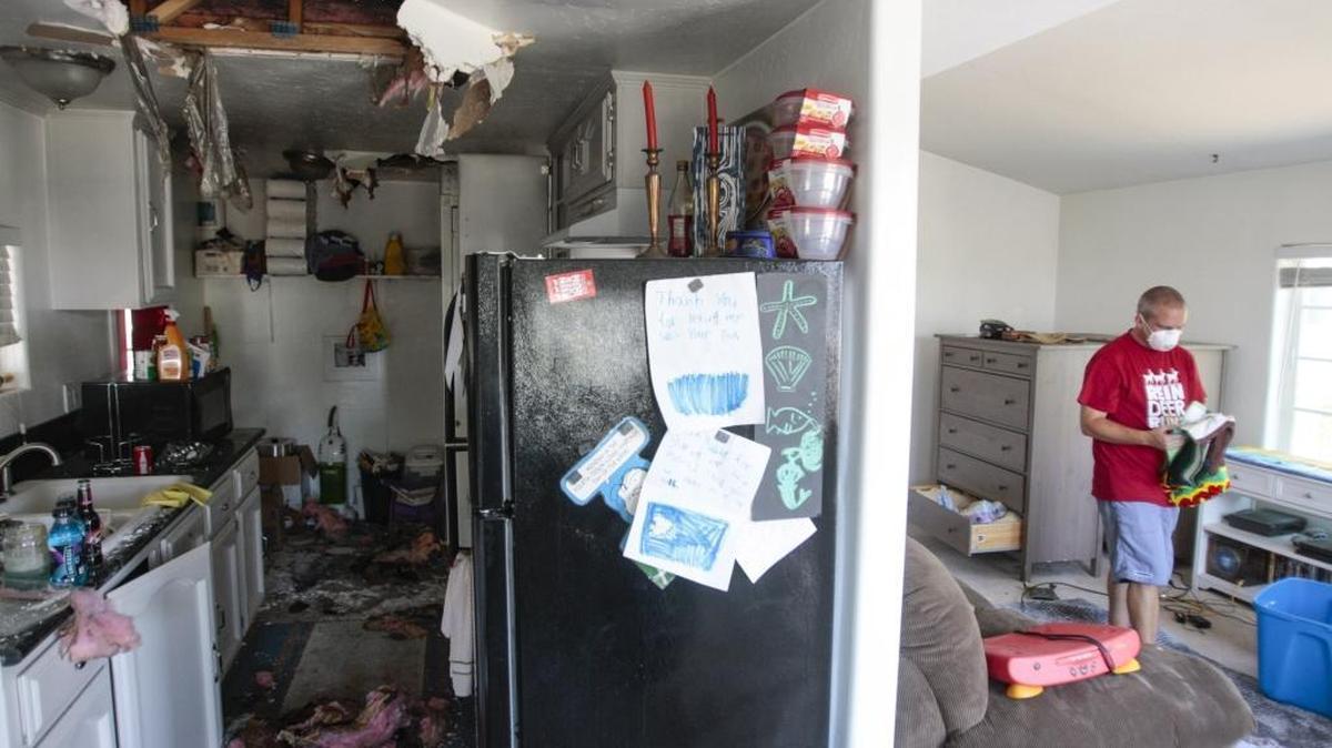 Shawn Tucker wears a mask as he recovers what he can from the mobile home he and his wife Katie rent in Atascadero. Two mobile homes were heavily damaged after a fire near San Diego Way in Atascadero.