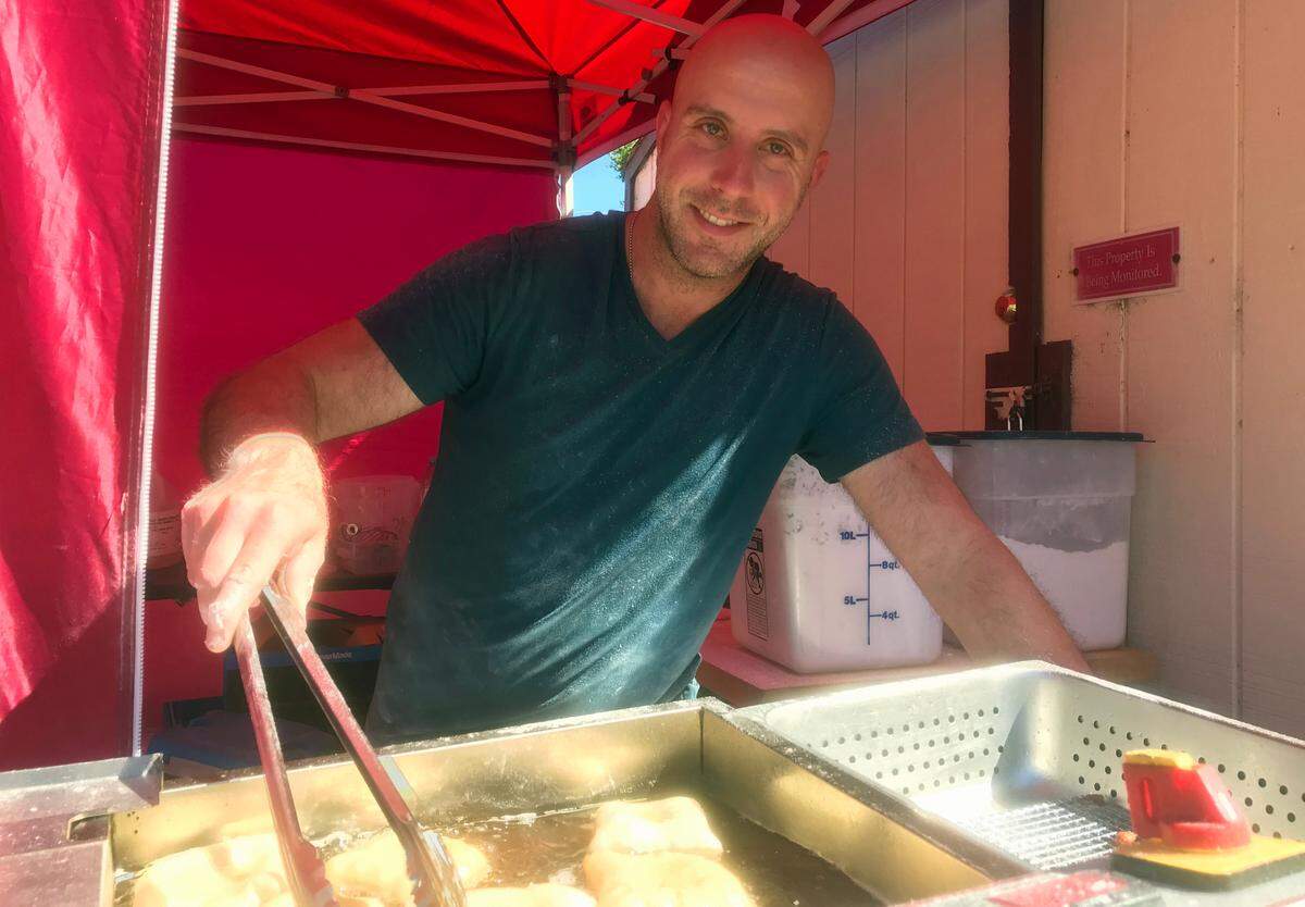 David Perlis, owner of The Second Line, fries his signature beignets at the Cambria farmers market in June 2022.