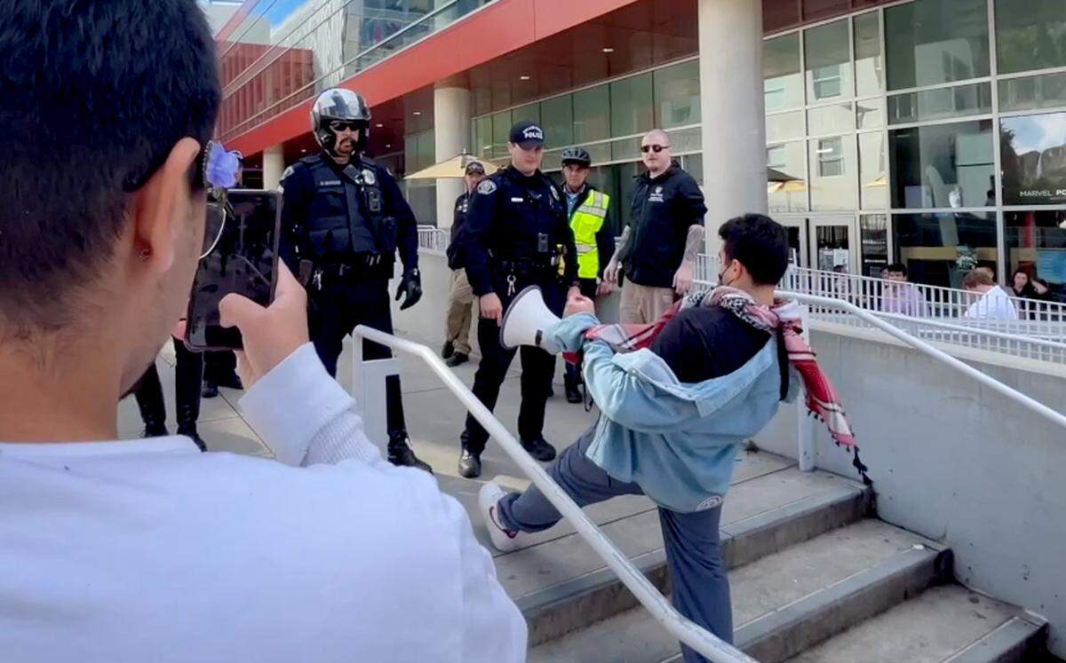 While a student videos, Cal Poly student Samir Ibrahim reaches his foot out onto the top step outside the Cal Poly Rec Center after police told protesters to leave following a clash between officers and pro-Palestine demonstrators on Tuesday, Jan. 23, 2024.