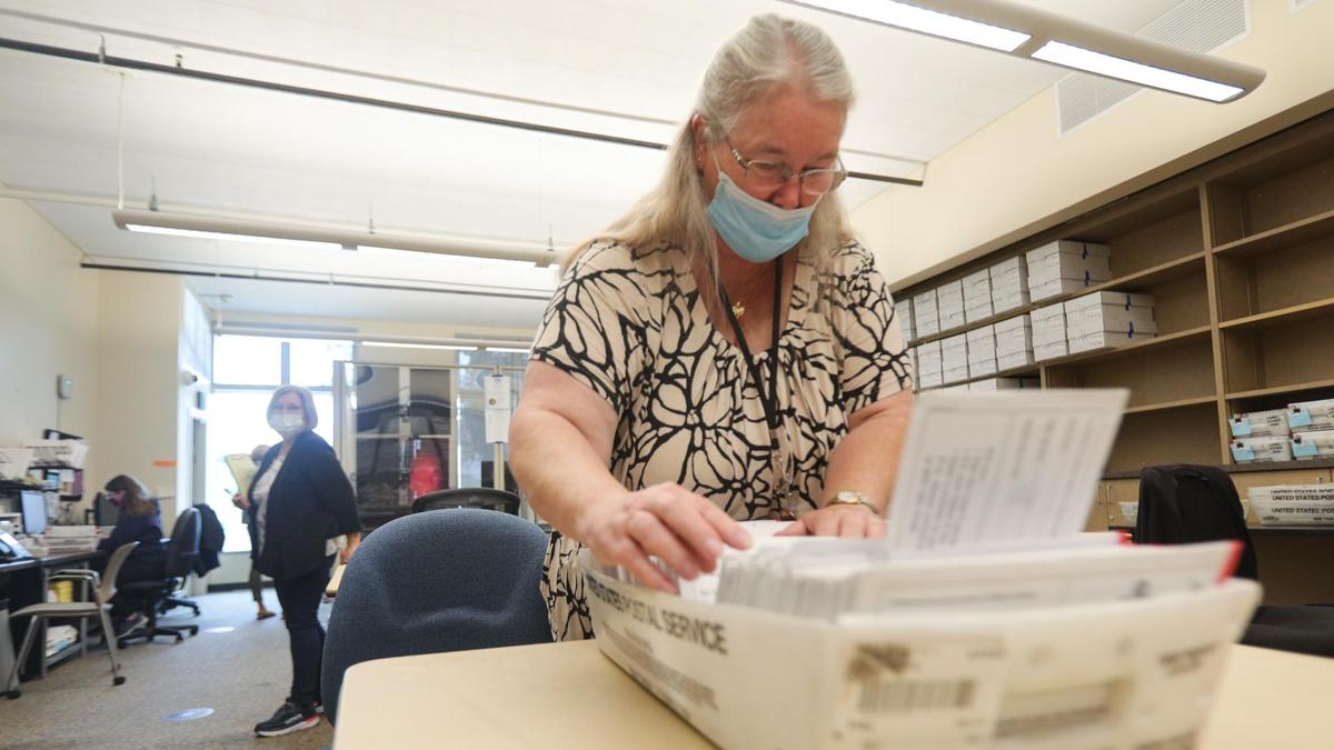 A poll watcher, left, who declined to give her name stands in the San Luis Obispo County elections office as Gayla Beck, a temporary elections employee, alphabetizes envelopes that contained mail-in ballots cast in the 2021 gubernatorial recall election. Observers from the Election Integrity Project have been watching the vote-counting process since August.