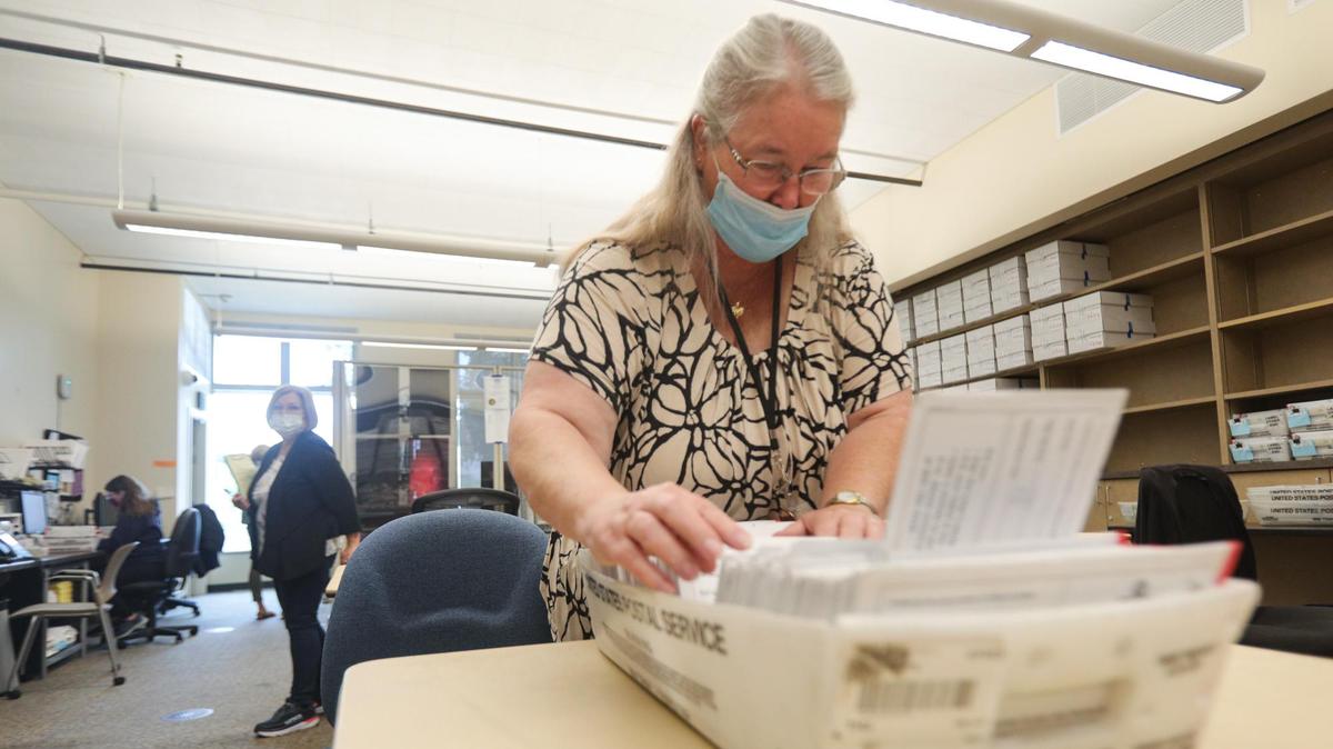 In this Sept. 2021 file photo, a poll watcher, left, who declined to give her name, stands in the San Luis Obispo County elections office. In the foreground Gayla Beck, a temporary elections employee, alphabetizes envelopes that contained mail-in ballots cast in the 2021 gubernatorial recall election.