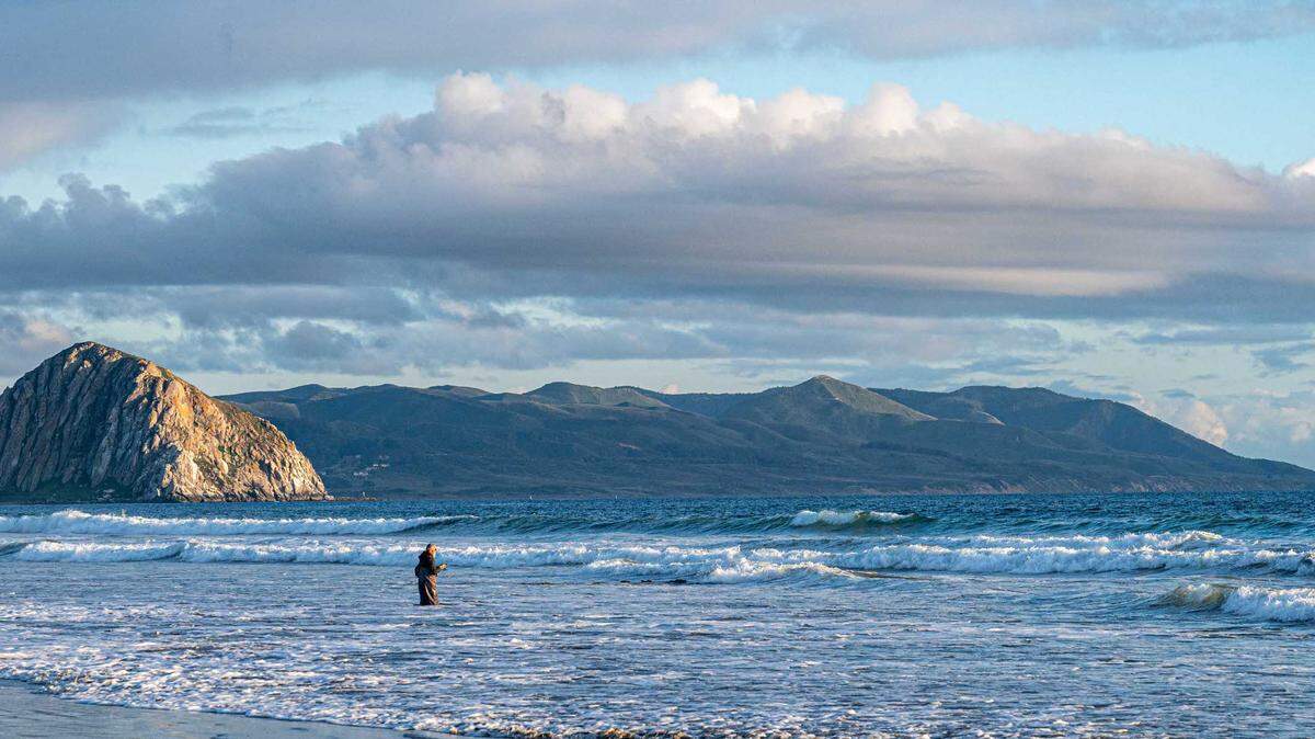 A man waded into the Pacific Ocean to fish near Morro Rock.