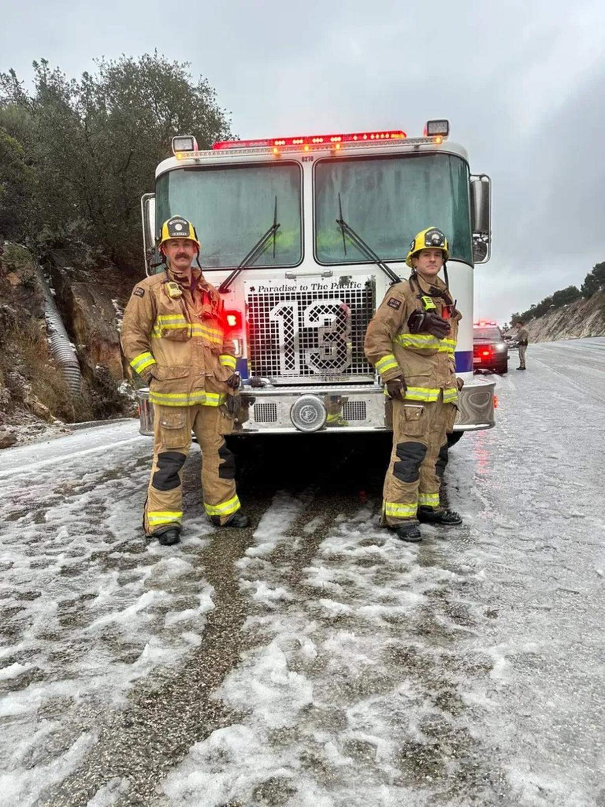 Firefighters from Santa Barbara County stand in snow and slush on Highway 154 on Sunday, Jan. 26, 2025.