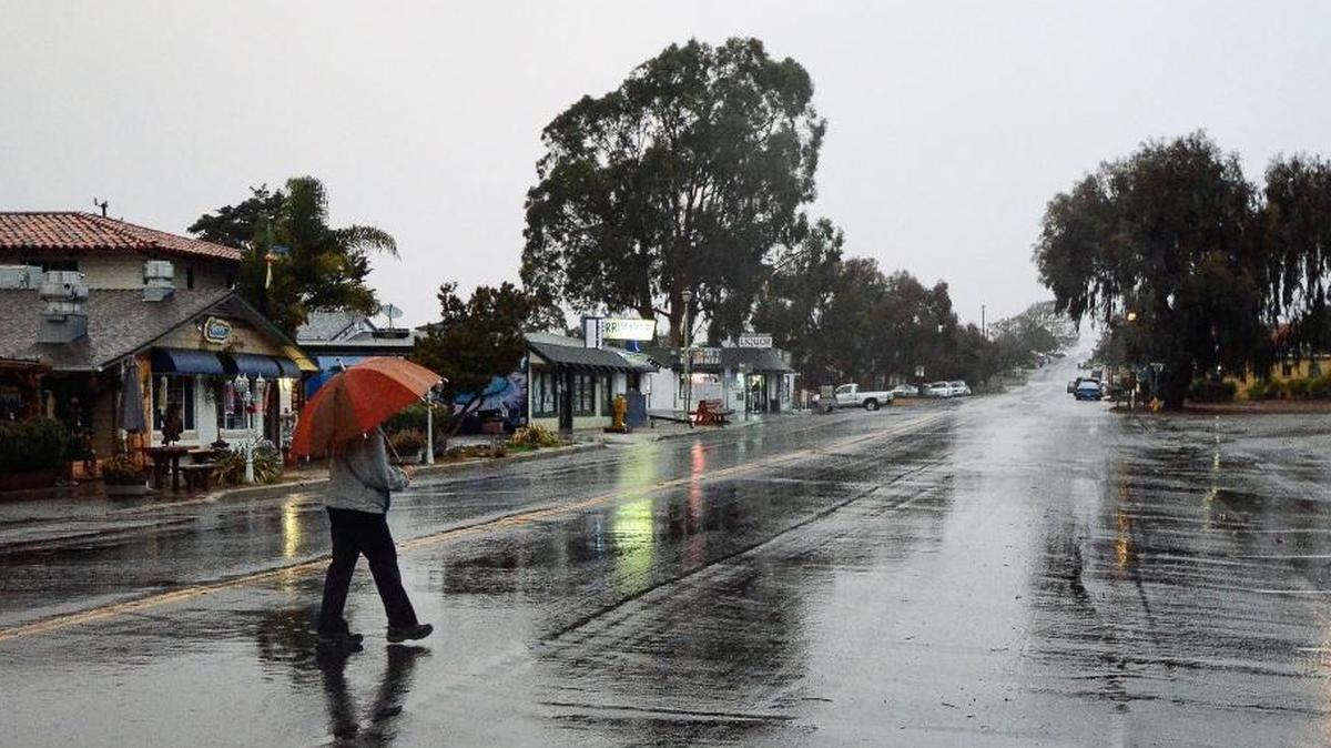 A pedestrian crosses the street in the rain at Baywood Park last year.