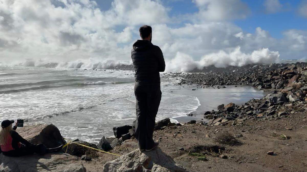 Powerful waves crash over the breakwater in Morro Bay on Saturday, Dec. 30, 2023, as spectators watch from behind caution tape on the south side of Morro Rock.