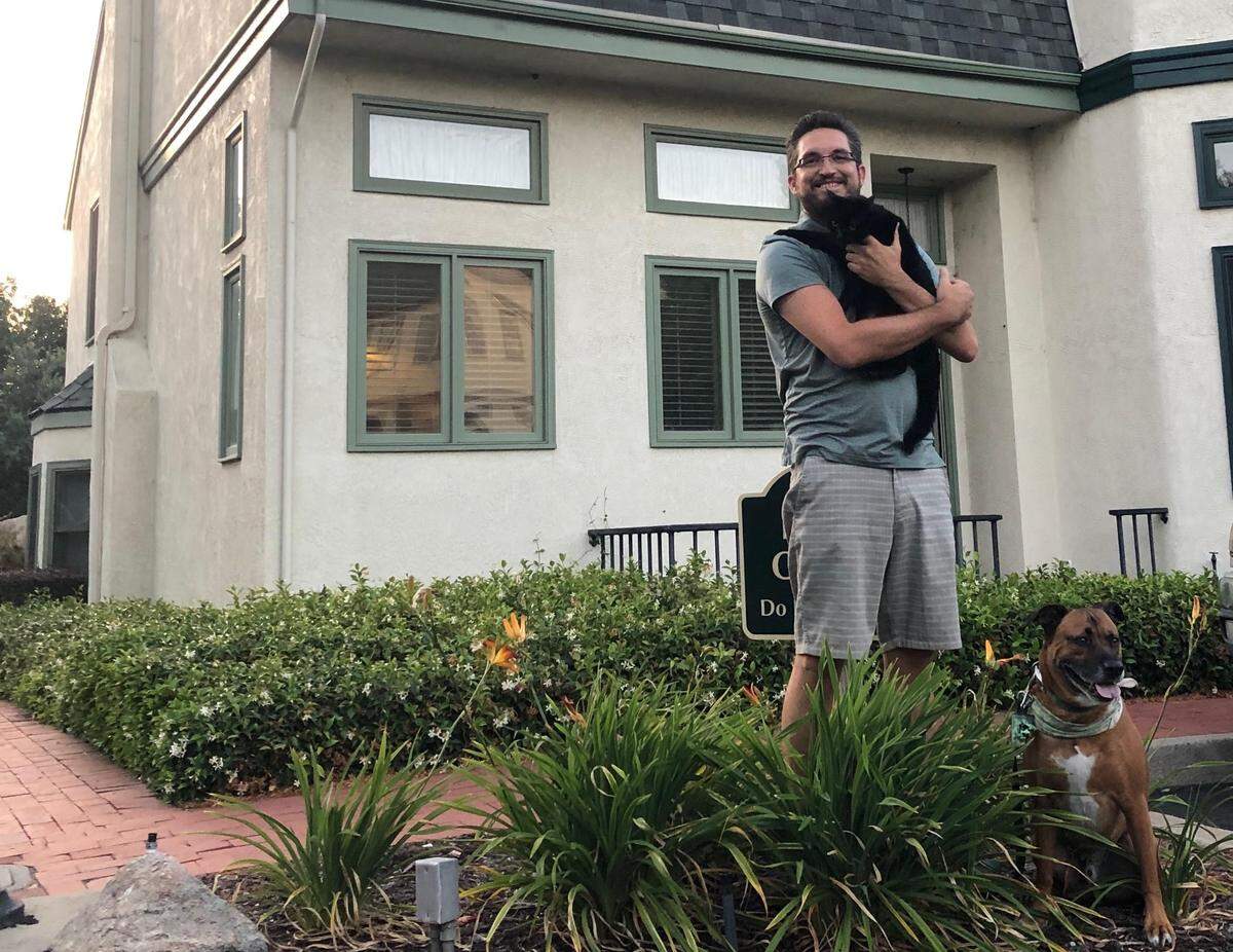 Kristian Olsen stands with his pets outside the condo he bought in May 2019. Olsen’s job as a Bay Area software engineer helped him save up enough money to purchase his home.