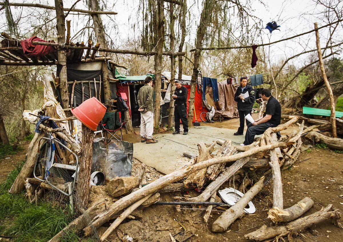 Detective Eric Azarvand, center, and community services officer Alissa Reina meet with two occupants of a large camp structure in the Salinas riverbed as they and other members of the Paso Robles Police Department make contact with people living in a homeless camp to warn them of an upcoming cleanup in this 2016 file photo.