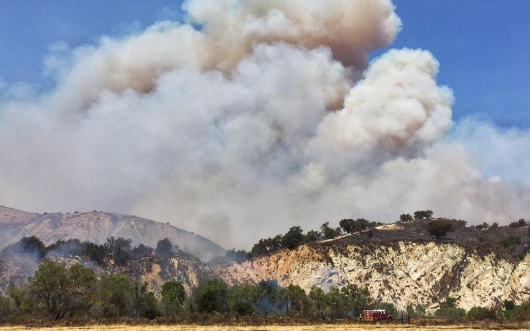 A Santa Barbara City Fire engine is dwarfed by a large column of smoke from the Rey Fire on Friday afternoon.