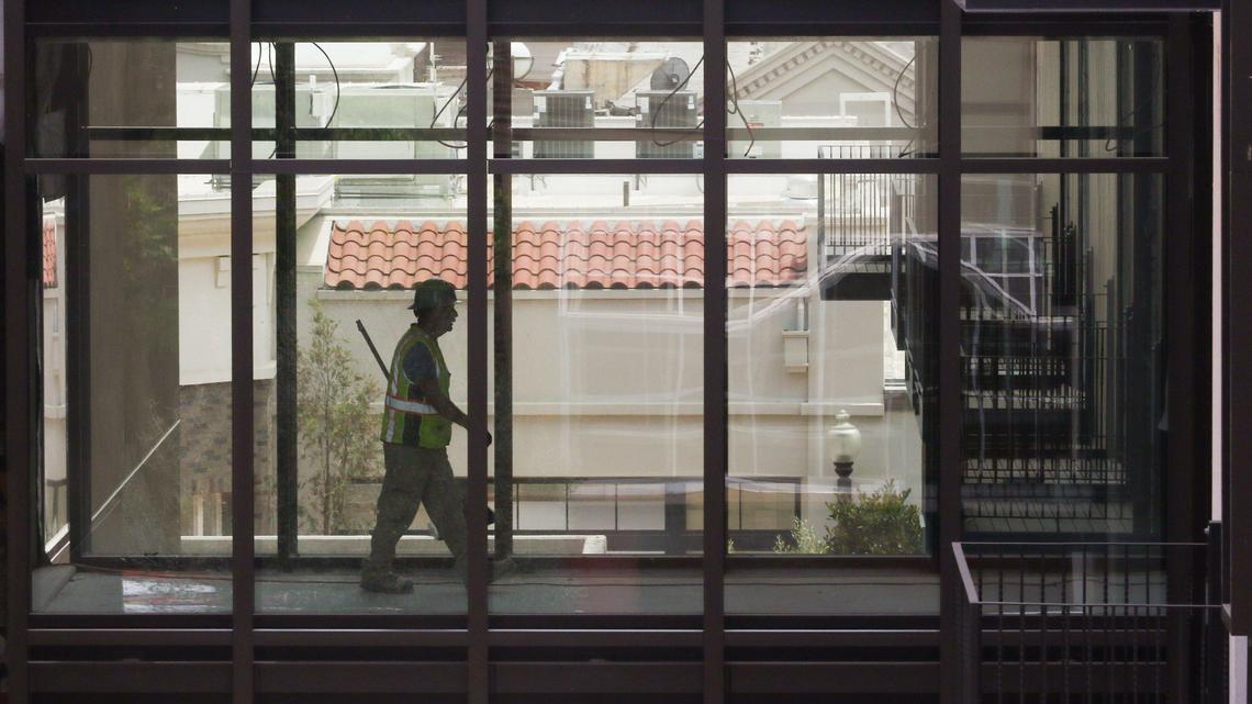 Worker at Hotel San Luis Obispo on Palm St. on a walkway between buildings.