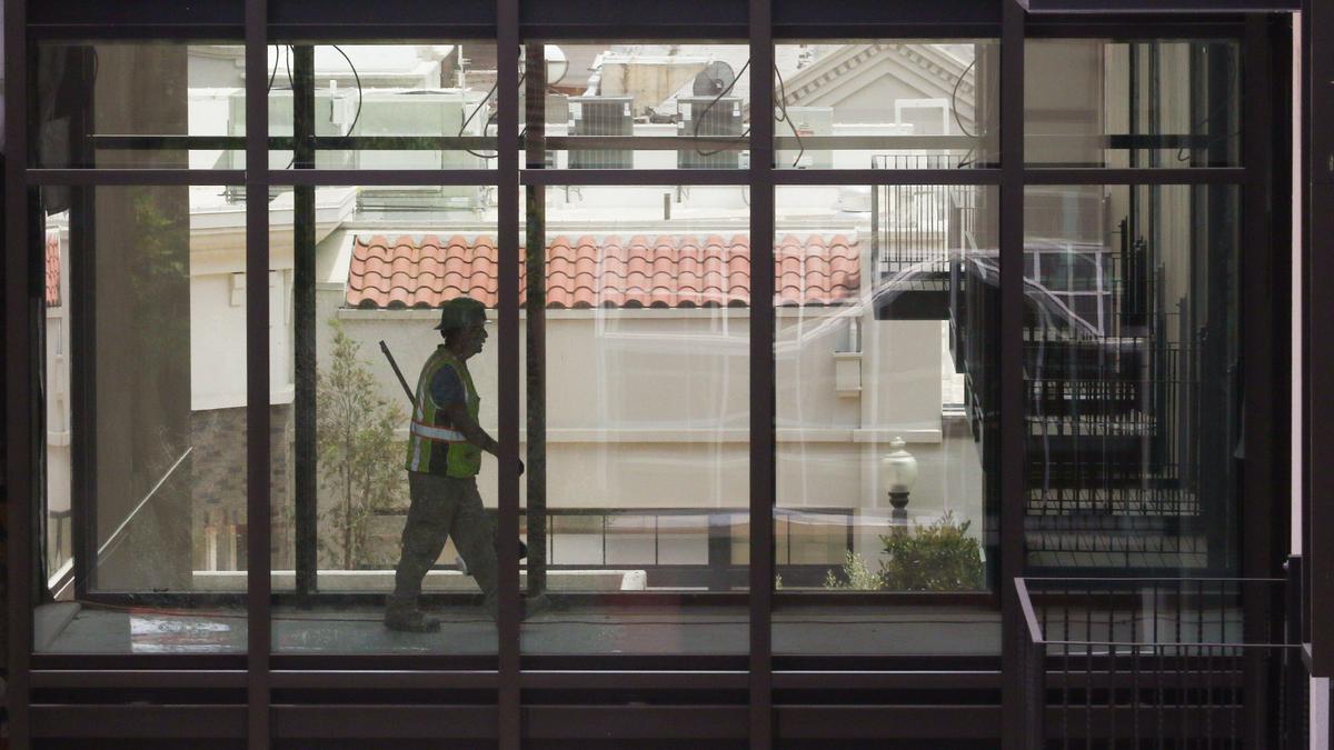 Worker at Hotel San Luis Obispo on Palm St. on a walkway between buildings.