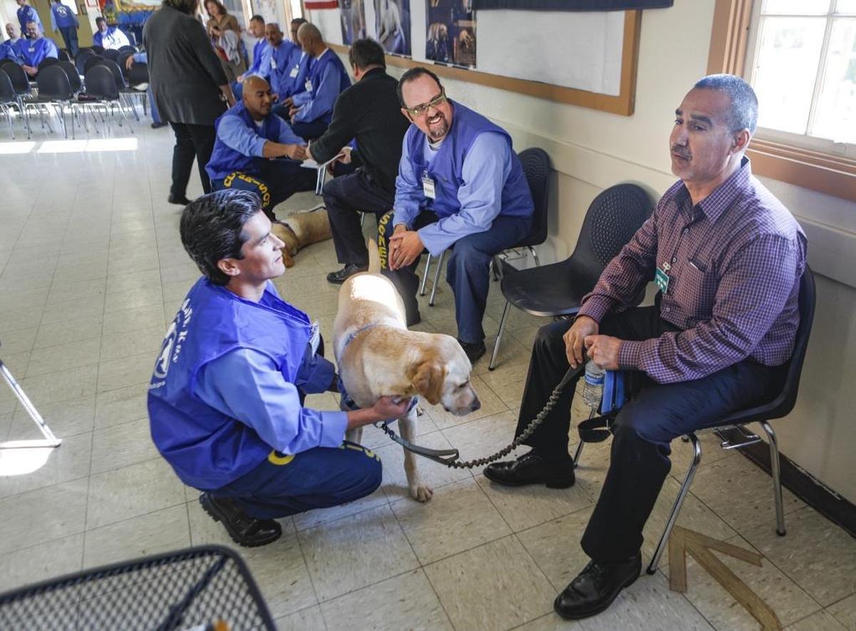 Christopher Bain, left, and Wesley Bird were inmate trainers for Rusty, a service dog presented to Henry Garcia. A program at California Men’s Colony teaches inmates to train dogs for service to veterans and first responders.