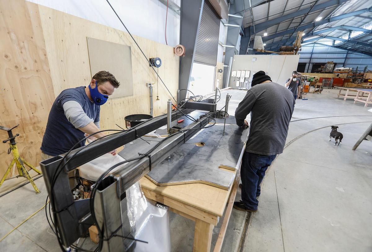Chad Peterson, left, and Pedro Arellano cut plastic protective gowns using a template that was manufactured in-house. Daniels Wood Land in Paso Robles typically creates playground equipment, movie props and tree houses. Due to the coronavirus outbreak, the company has shifted gears to produce plastic gowns for emergency workers and hospitals.
