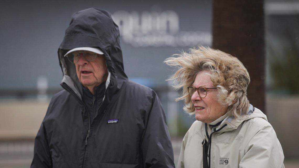 Rob and Tess, vacationing from New York, walk next to Pismo Pier in 23 mph winds as a storm came to Pismo Beach on Feb. 13, 2025.