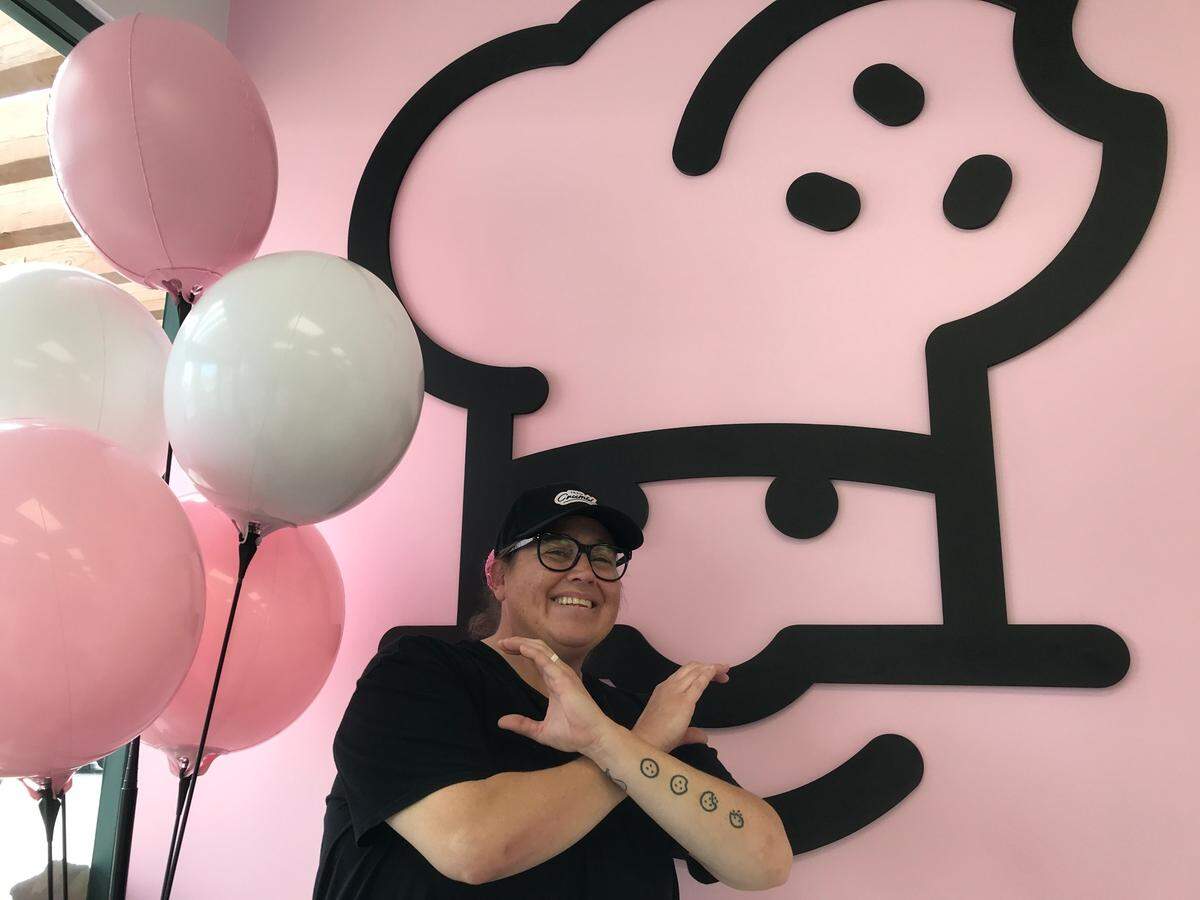 Julie Packnett, co-owner of the new Paso Robles Crumbl Cookies shop, poses for a picture while flashing the Crumbl Crew hand gesture. She also co-owns Crumbl Cookies stores in Pismo Beach and Santa Maria.