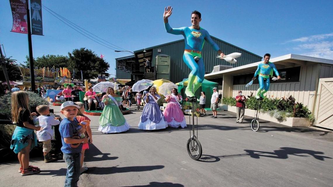 The Midway Spectacular parade makes its way through the California Mid-State Fair led by the unicycling juggling duo Something Ridiculous.
