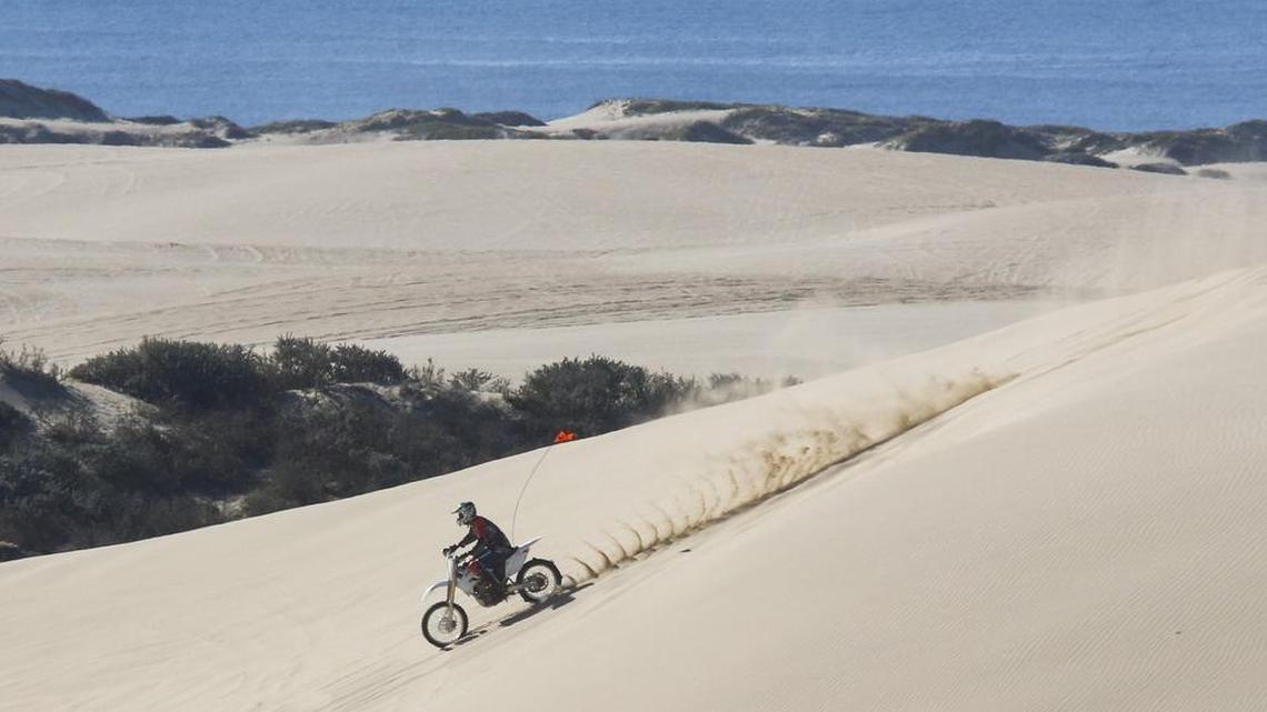 A dirt bike rider cruises down a hill at the Oceano Dunes State Vehicular Recreation Area.