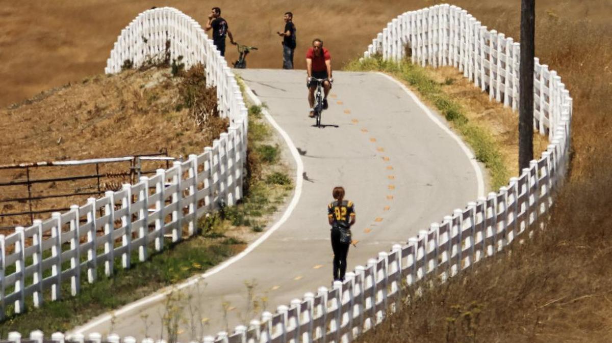 Walkers and cyclists move along a bike path Wednesday near the Madonna Inn in San Luis Obispo. The valley’s coastal area has experienced highs in the 70s so far this week, and highs are expected to be in the 80s by the weekend.