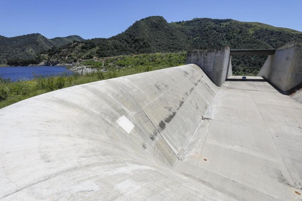Mark Hutchinson, deputy director of SLO County Public Works, leads tour of the Lopez Dam spillway in May. To give a sense of scale, a car is parked in a shadow under bridge.