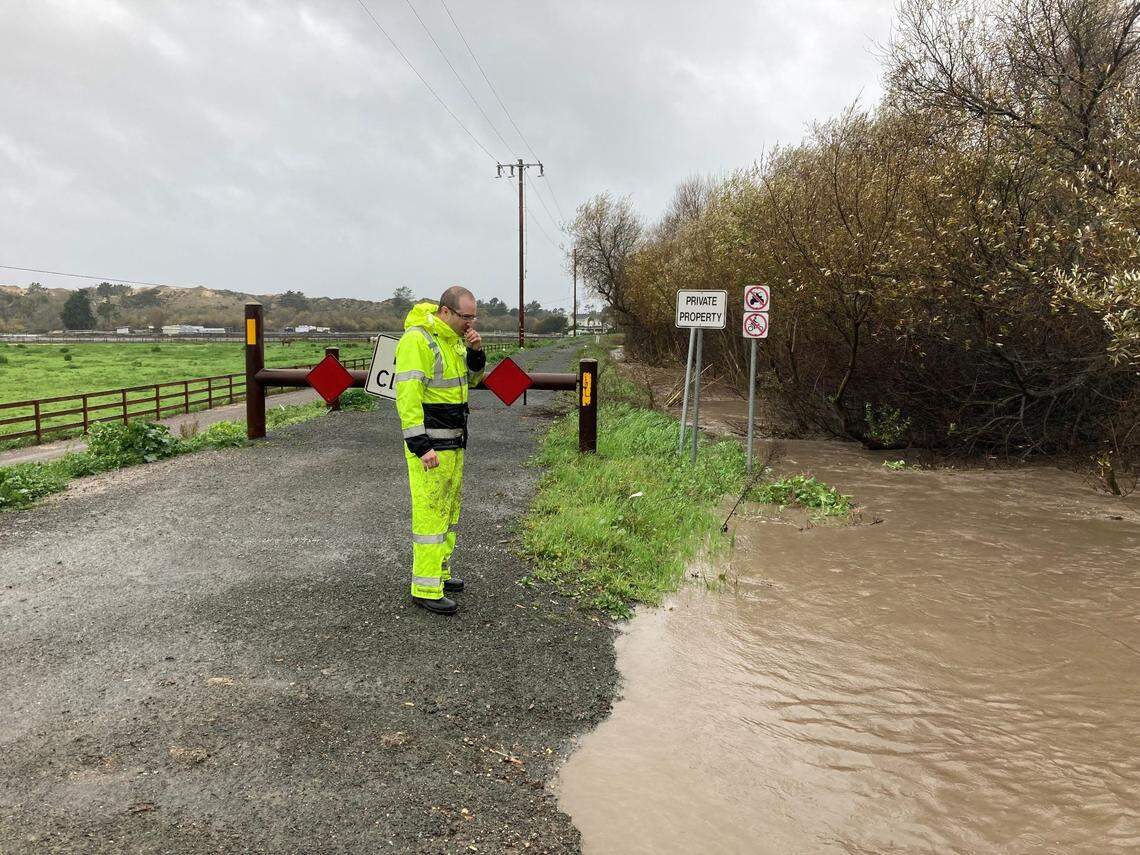 A SLO County worker surveys the a rising Arroyo Grande Creek from the levee as rain continues to fall on Jan. 9, 2023.