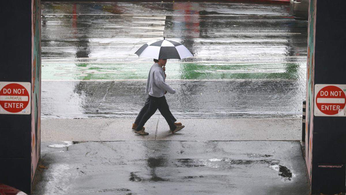 Two people share an umbrella, walking in step, up Marsh Street in San Luis Obispo on Nov. 11, 2024.