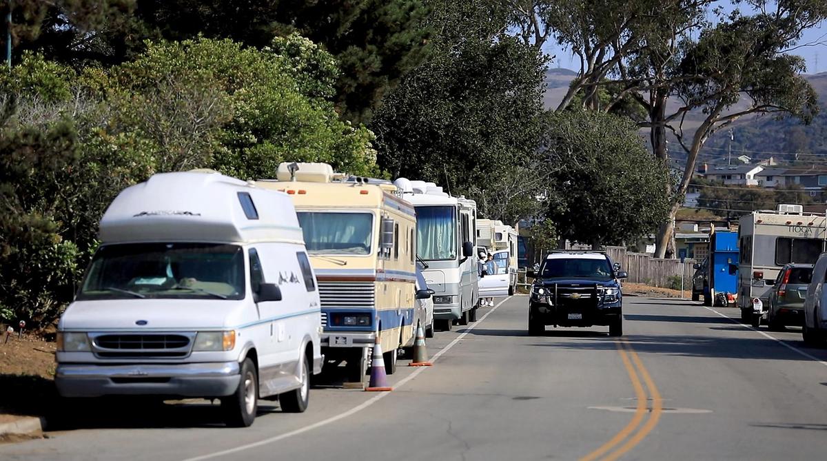 A San Luis Obispo County sheriff’s deputy drives down Palisades Avenue in Los Osos, where dozens of unhoused people live in a collection of RVs, vans and other vehicles. Those who live on the street say they’ve built a community, but neighbors feel uncomfortable accessing a nearby park, community center and library.