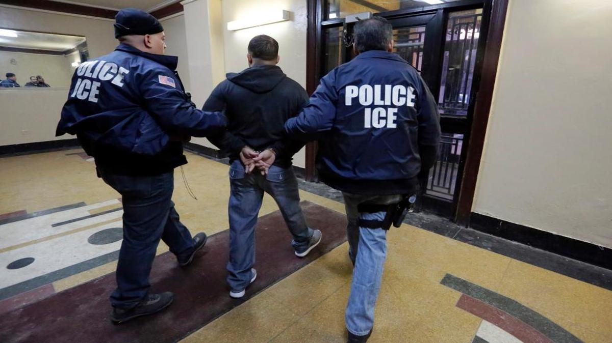 Immigration and Customs Enforcement officers with an arrestee during an early morning raid in New York in 2015.