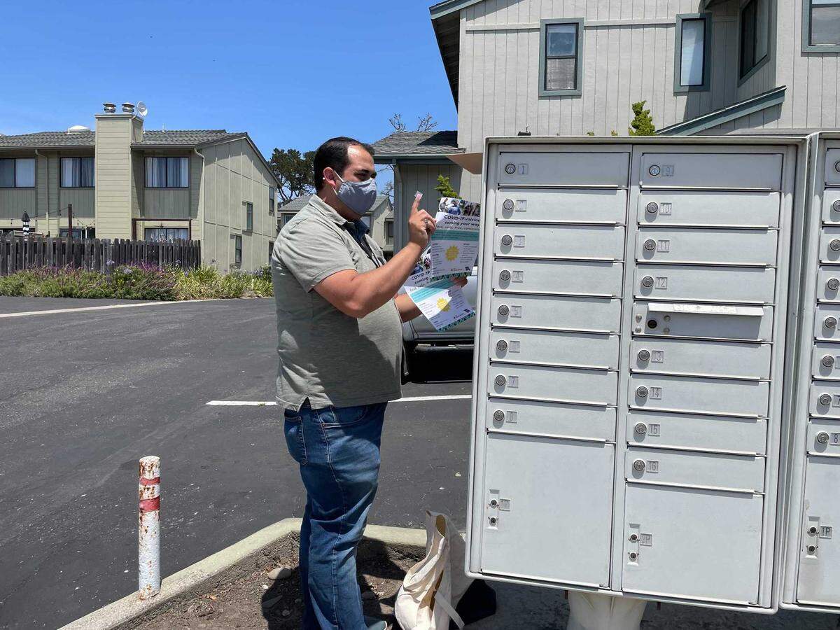 Felipe Gonzalez hangs flyers advertising a San Luis Obispo County Public Health Department coronavirus vaccine clinic on a mailbox in San Simeon. Gonzalez is the agency’s multilingual outreach coordinator, which involves canvassing in communities with lower vaccination rates and distributing information about nearby shot clinics.