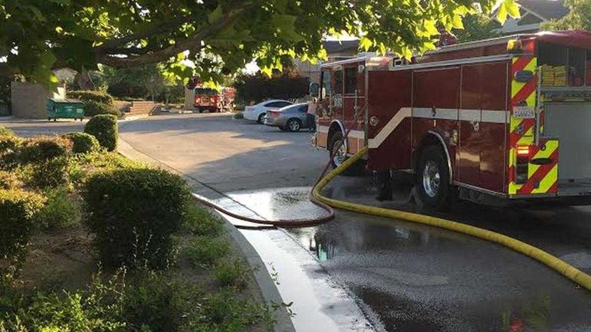 Firefighters battle a grass fire in an empty lot in Paso Robles