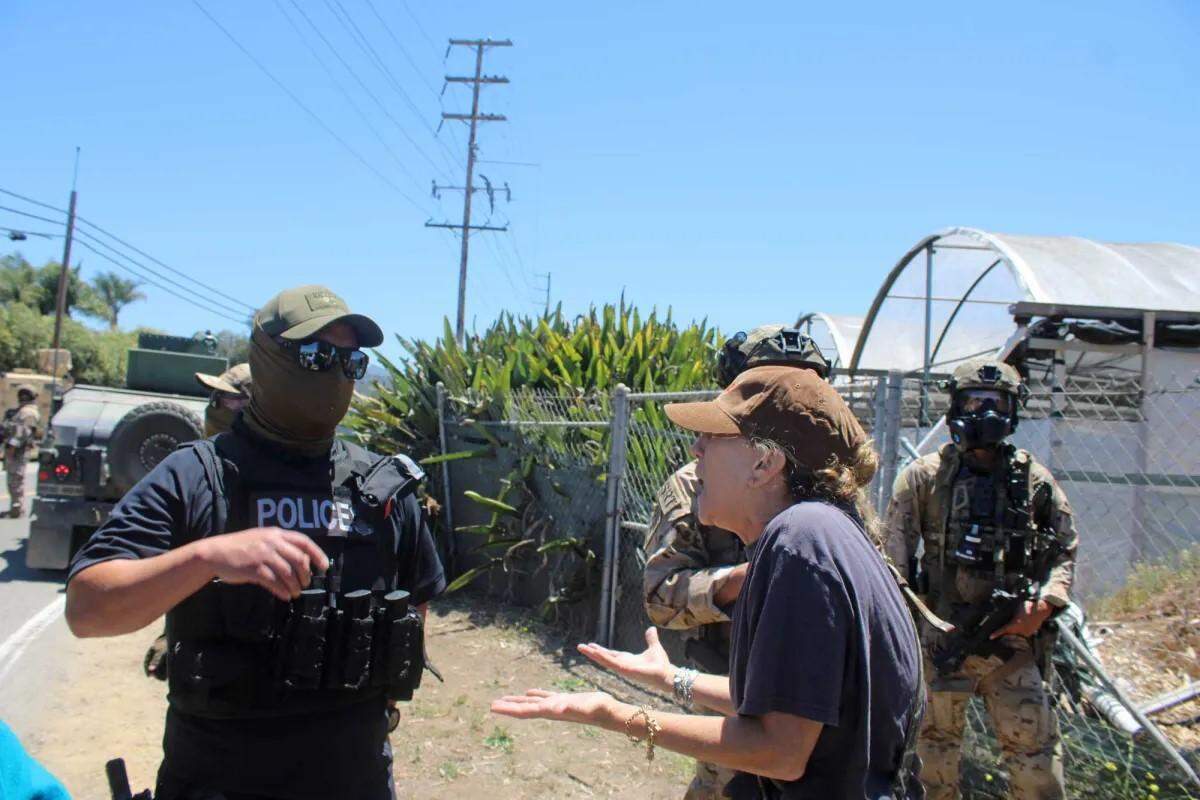 A protester confronts federal agents conducting an immigration enforcement operation at a Carpinteria cannabis farm on July 10, 2025. Ten workers were reportedly detained.
