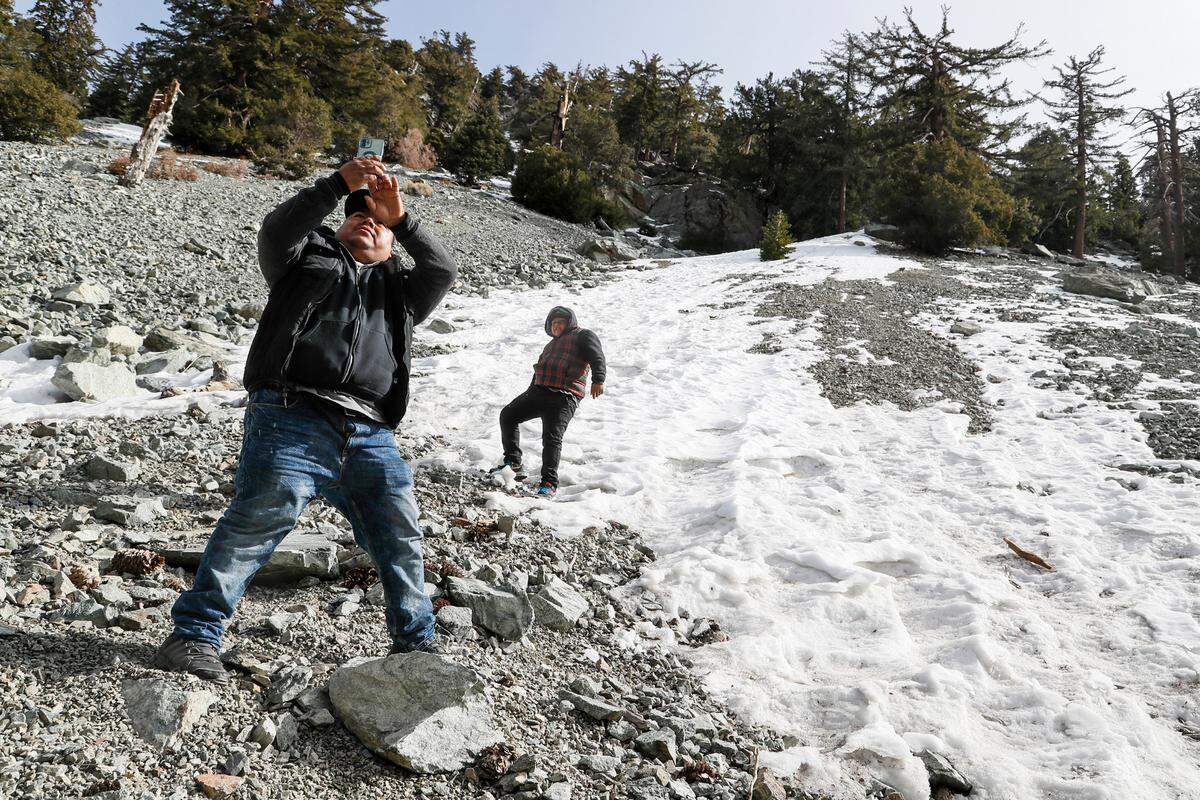 Marco Martinez Morales snaps a photo with his son, Marco Jr. as they frolic on a snowy roadside near Mt. Baldy in 2023.